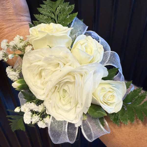 White rose and ranunculus wrist corsage with baby's breath and sheer ribbon.