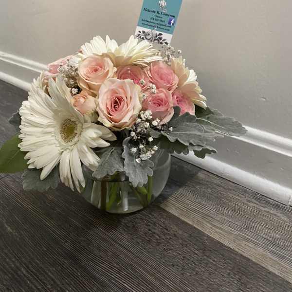Pink roses and white daisies arranged in a glass bowl vase