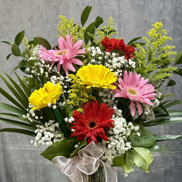Bouquet of pink, red, and yellow gerbera daisies in a glass vase