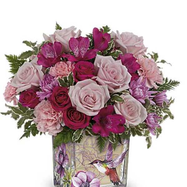 Pink and magenta bouquet in a square glass vase with a hummingbird design