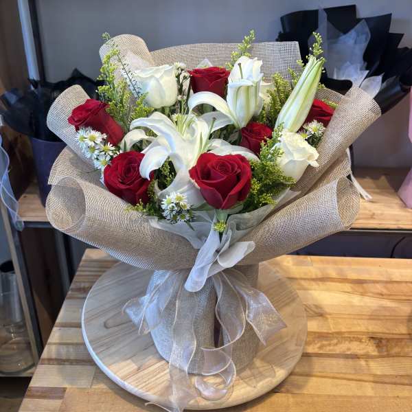 Bouquet of red roses and white lilies wrapped in beige paper