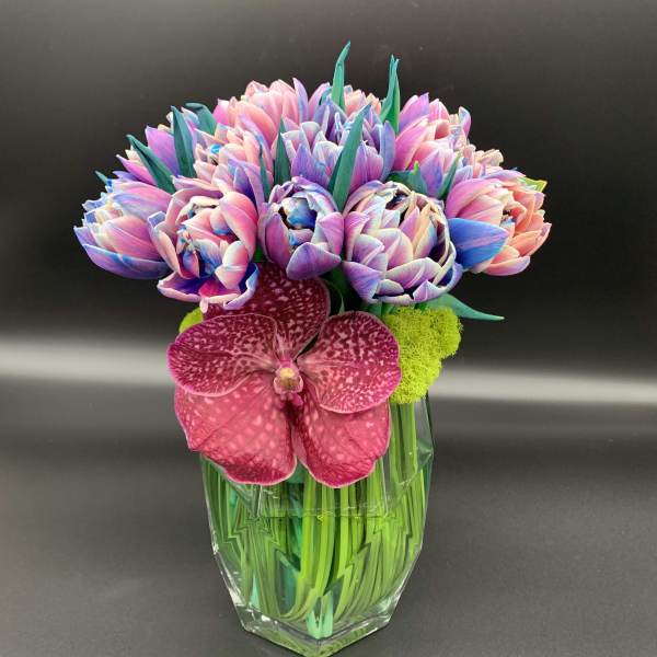 Colorful bouquet in a clear glass vase with a pink orchid front