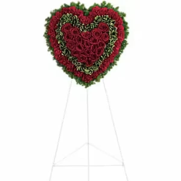 Heart-shaped standing floral tribute with red roses and green edging on an easel