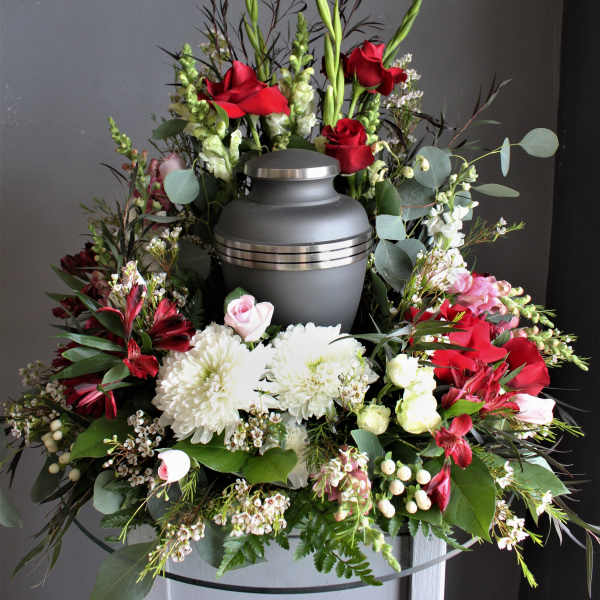 Funeral urn surrounded by red and white flowers in a wreath arrangement