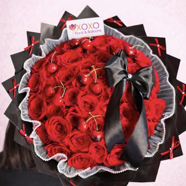 Large bouquet of red roses with a black ribbon and decorative wrap