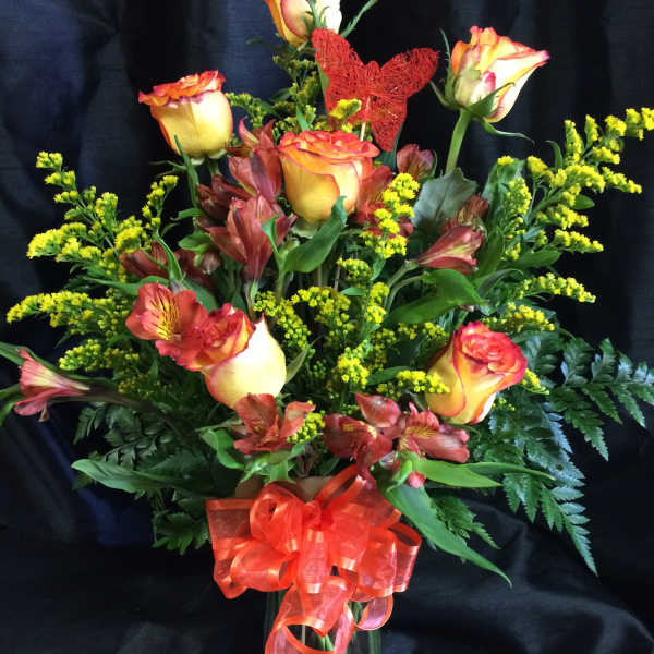 Bouquet of orange-yellow roses and red alstroemeria in a glass vase