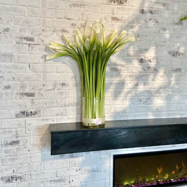 Tall bouquet of white calla lilies in a clear glass vase