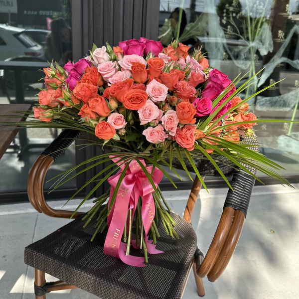 Large bouquet of pink and orange roses tied with a pink ribbon