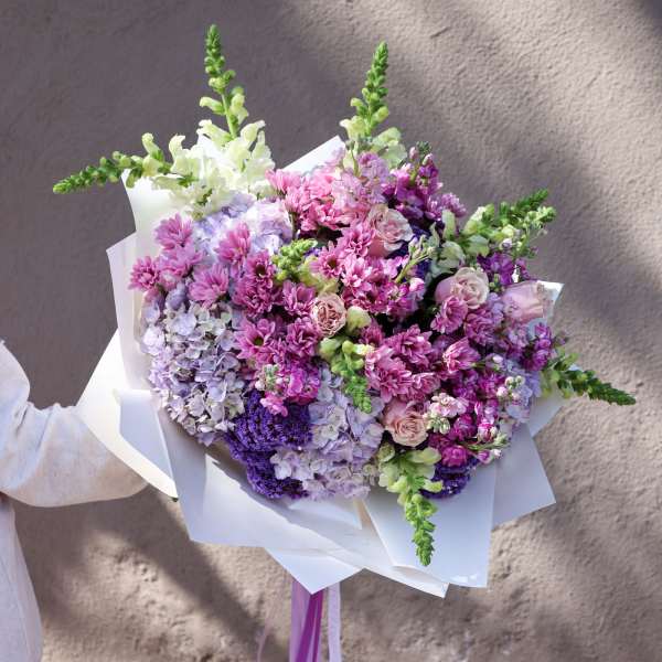 Bouquet of pink, purple, and white flowers wrapped in white paper