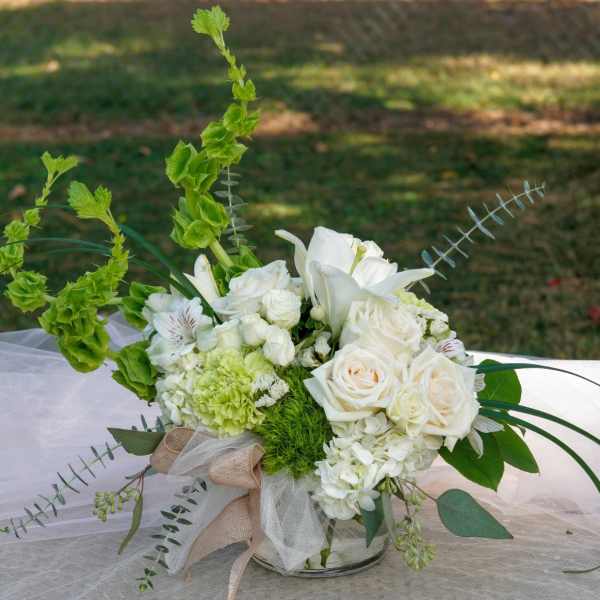 White floral arrangement with roses and lilies in a glass vase