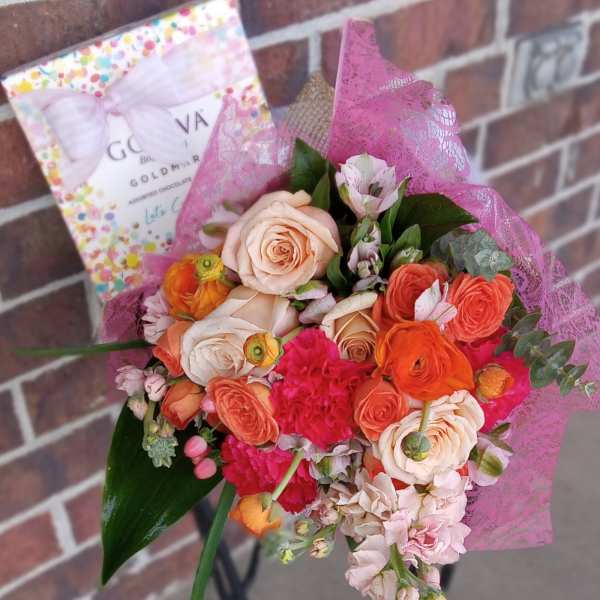 Bouquet of peach and coral roses with pink flowers and a chocolate box
