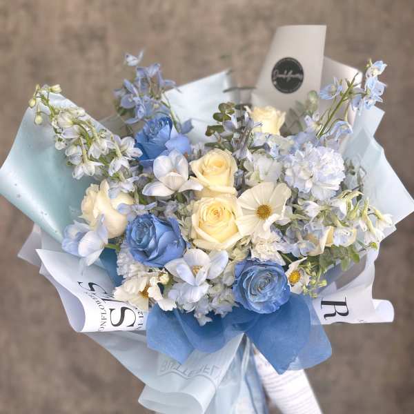 Bouquet of blue and cream roses with pale blue flowers wrapped in paper