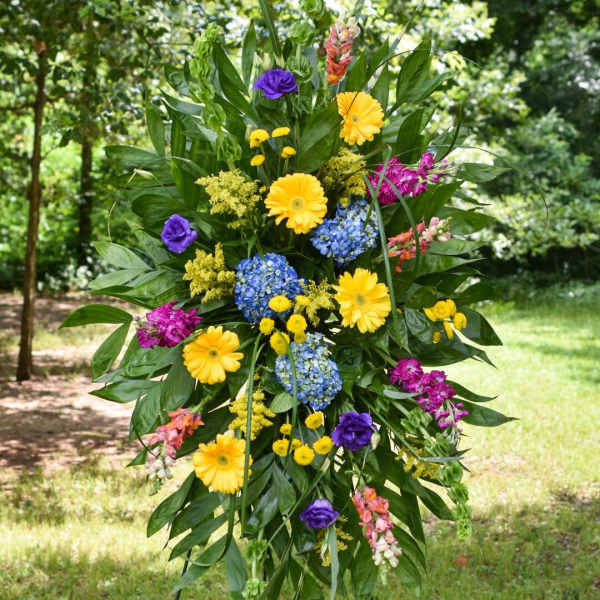 Tall standing floral spray with yellow, blue, purple, and pink blooms