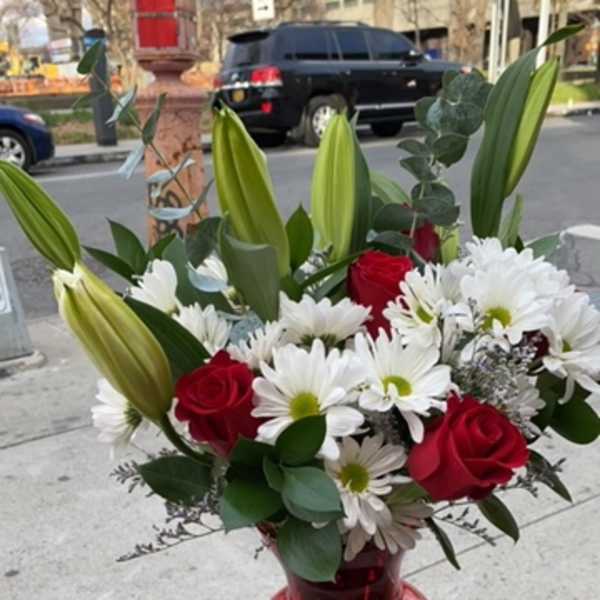 Red roses and white daisies in a red glass vase