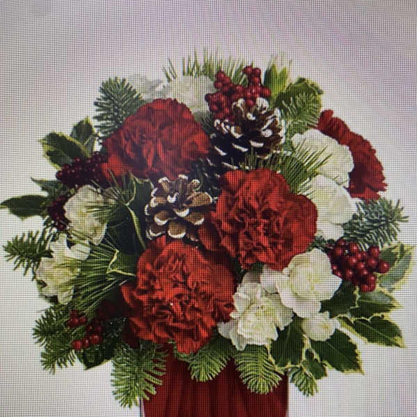 Red and white floral arrangement in a red vase with pinecones and berries