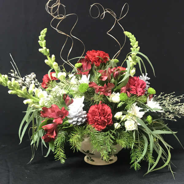 Red and white floral arrangement in a ceramic vase with curly wire accents