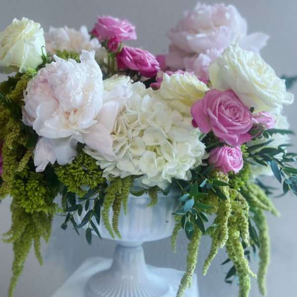 Pink and white roses with hydrangeas in a white pedestal vase