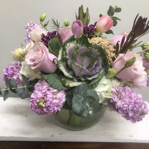 Pink tulips and roses in a glass vase with purple blooms