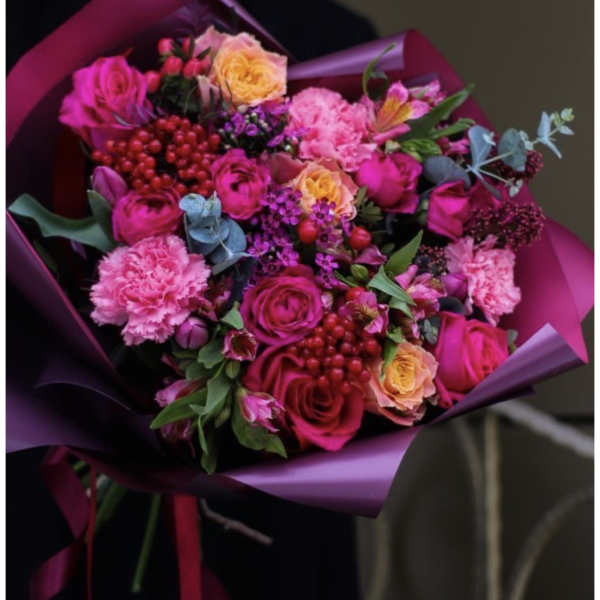 Bouquet of pink and peach roses with carnations wrapped in purple paper