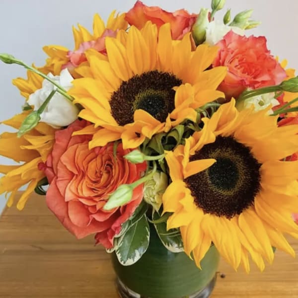 Bouquet of sunflowers and orange roses in a green vase