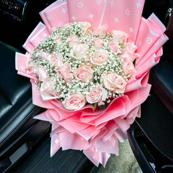Pink rose bouquet wrapped in pink paper with white filler flowers