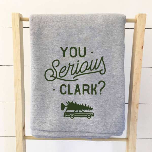 Gray folded shirt with green text on a wooden rack