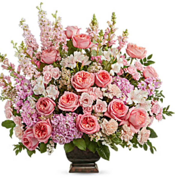 Pink roses and mixed blooms arranged in a dark vase
