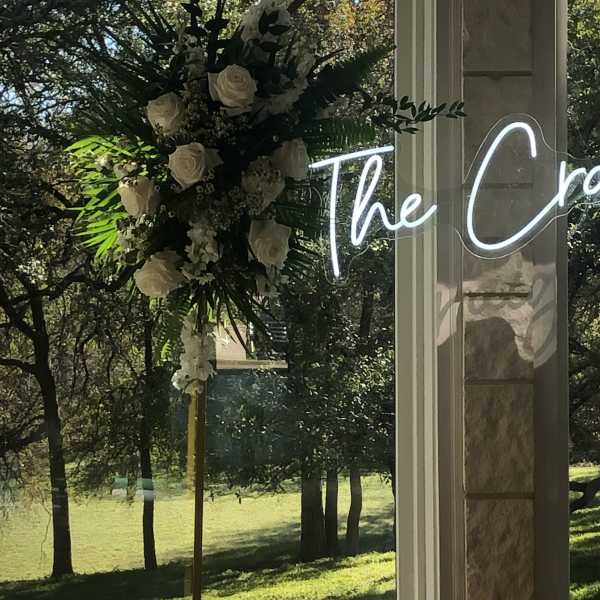 White rose floral arrangement on a tall stand by a window