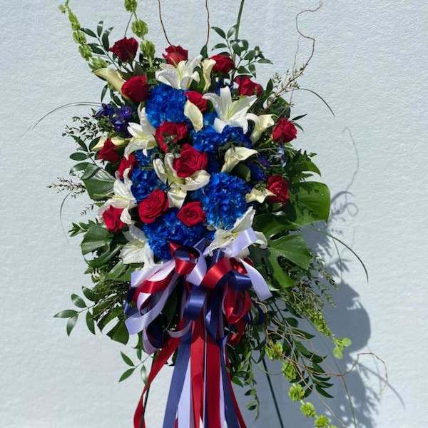Standing floral spray with red roses, white lilies, and blue hydrangeas