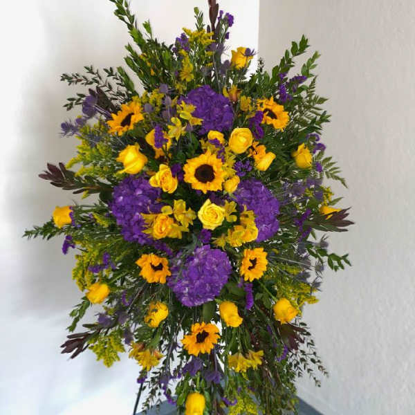 Large standing spray of yellow and purple flowers on an easel