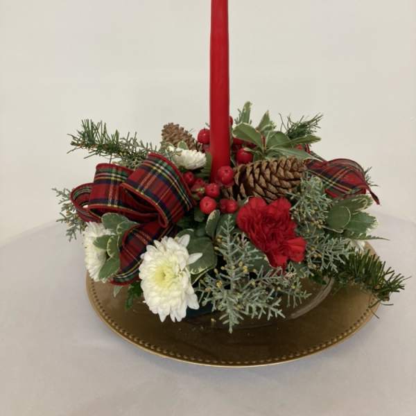 Holiday centerpiece with a red taper candle, pinecones, and white flowers