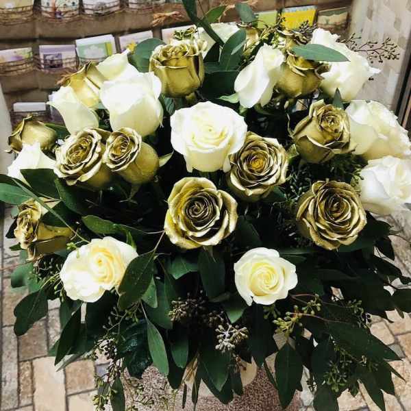 Bouquet of white and gold roses with dark green foliage