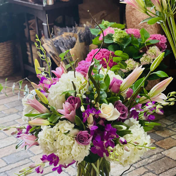 Mixed pink, white, and purple flowers in a clear glass vase
