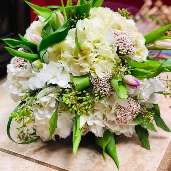 White floral bouquet with green leaves and pink buds