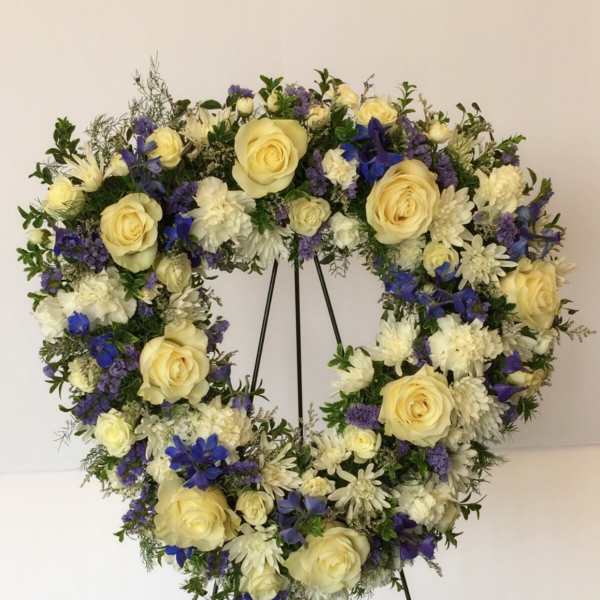Heart-shaped floral wreath with cream roses, white blooms, and blue flowers