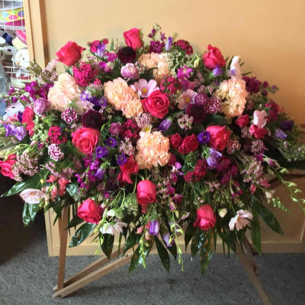 Large mixed flower spray with pink roses and purple blooms on a stand