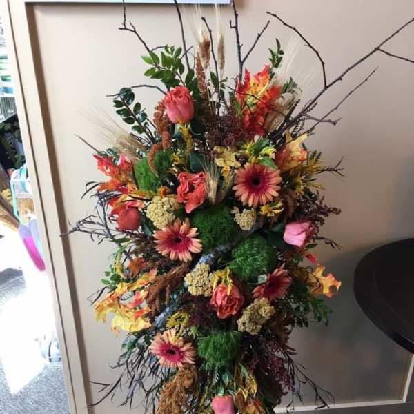 Tall mixed floral spray with pink and orange blooms on a stand