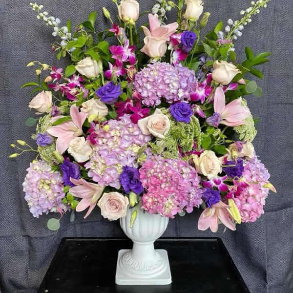 Large pastel floral arrangement in a white pedestal vase