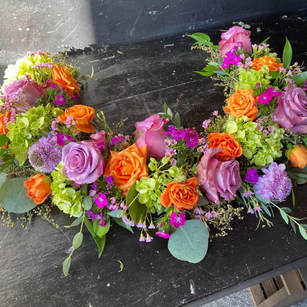 Colorful floral wreath with roses, hydrangeas, and small purple blooms