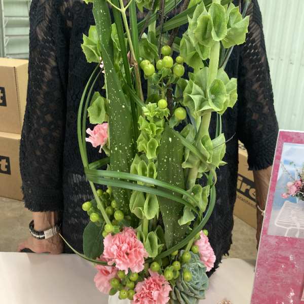 Tall green floral arrangement with pink carnations and berry accents
