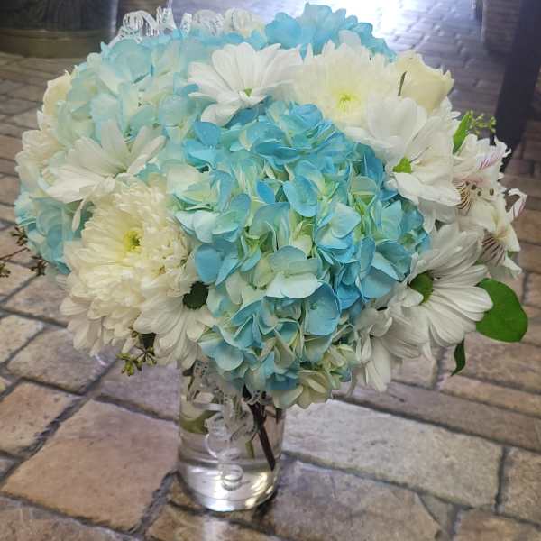 Blue hydrangea and white daisy bouquet in a clear glass vase
