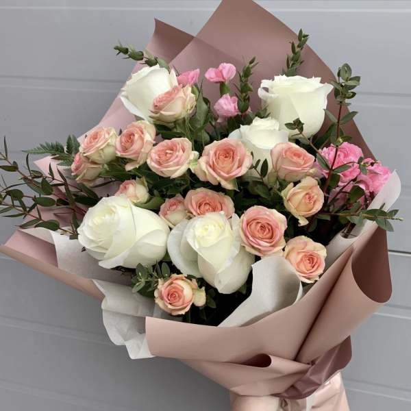Bouquet of white and blush pink roses wrapped in pink paper