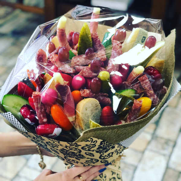 Bouquet of assorted salami, cheese, and grapes wrapped in decorative paper