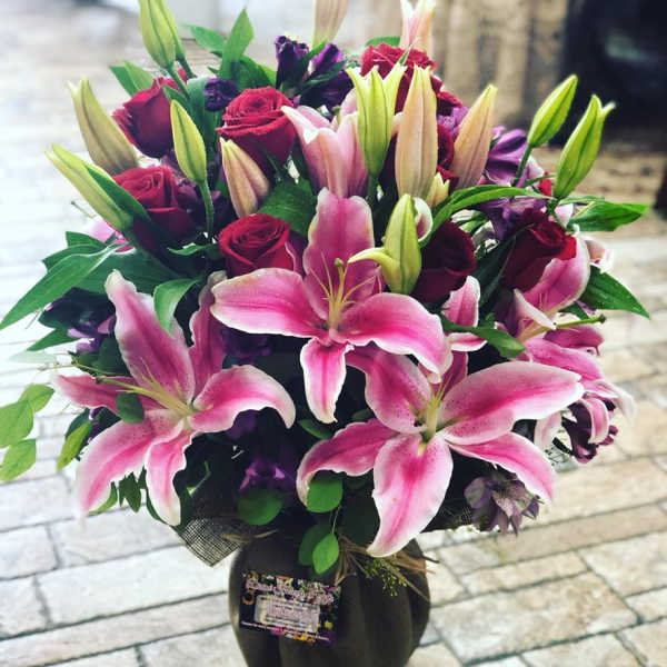 Bouquet of pink lilies and red roses in a dark vase