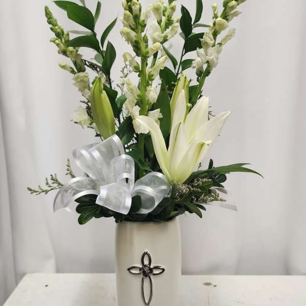 White lilies and snapdragons in a tall vase with a silver ribbon bow