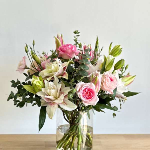 Pink roses and white lilies in a clear glass vase