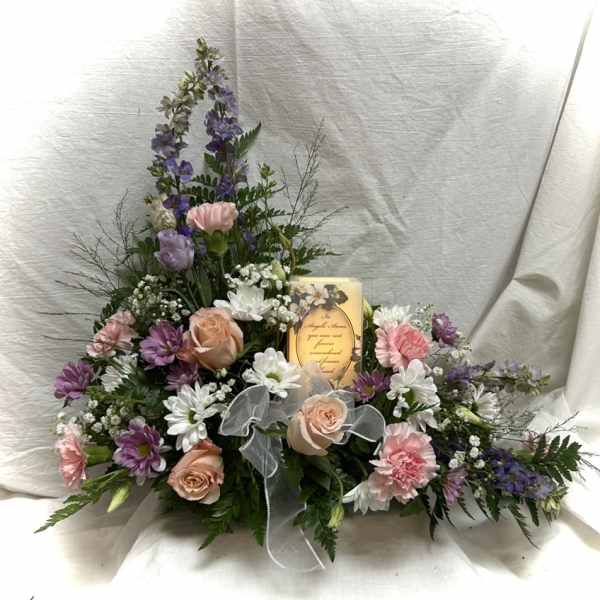Pastel floral arrangement with roses, carnations, and daisies around a candle
