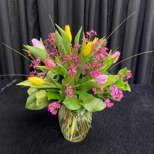 Bouquet of pink and yellow tulips in a clear glass vase