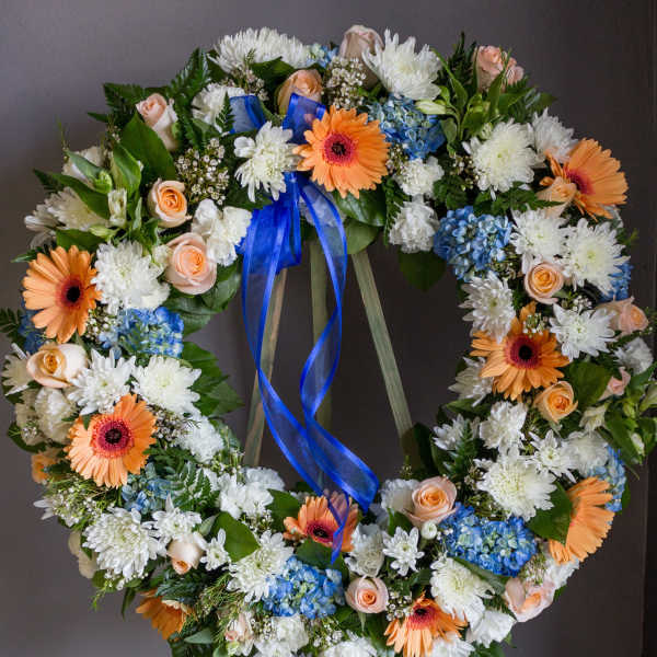 Floral wreath with white, peach, blue, and orange blooms on an easel