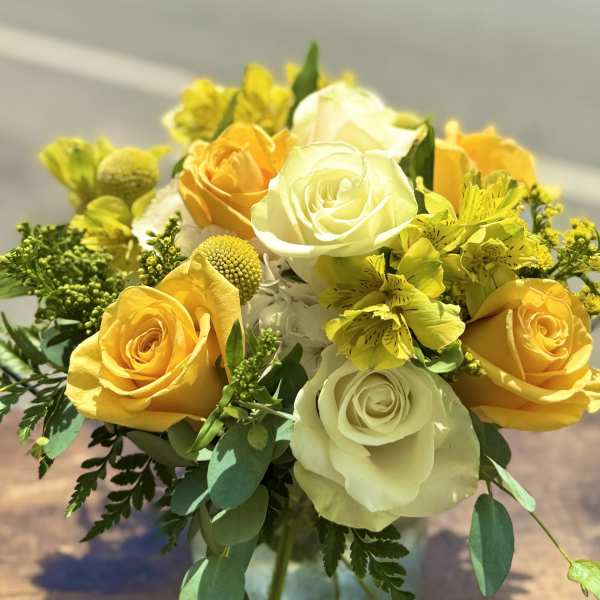 Yellow and white roses with yellow alstroemeria in a glass vase